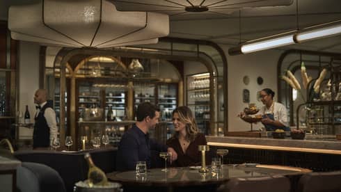 A man and woman drinking wine in a dimly lit restaurant.