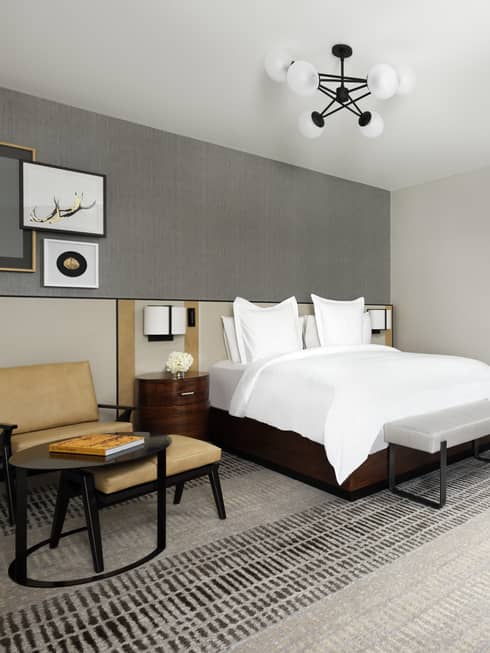 Fireplace, hotel bed and armchair in modern bedroom suite