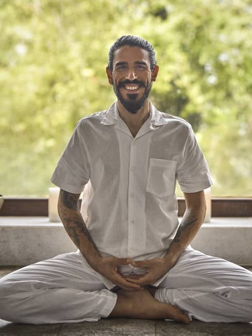 Portrait of Wellness Ambassador Jose Pablo Rodriguez, a man with dark hair and a beard wearing a white button-down short-sleeve shirt