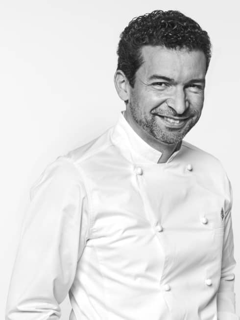 Guillaume Cabrol in white chef's coat, hands in pockets, smiling