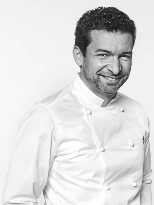 Guillaume Cabrol in white chef's coat, hands in pockets, smiling