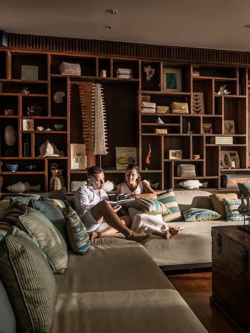 Couple relaxes on oversized plush L-shaped sofa by open door with flowing curtains