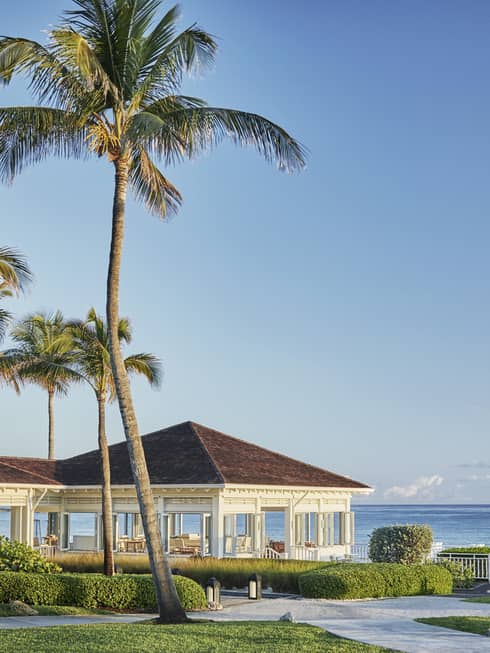 Oceanfront restaurant Dune's pavilions and palm trees, sunny skies over ocean