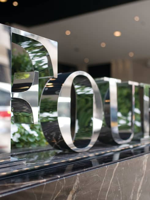 Large silver letters spelling Four Seasons along marble planter with white flowers