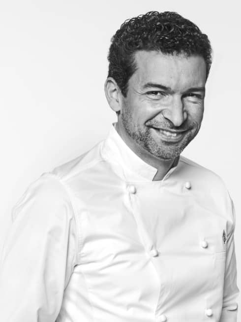 Guillaume Cabrol in white chef's coat, hands in pockets, smiling