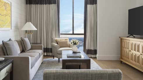 Living room with grey sofa, arm chair, TV, glass table lamps and windows