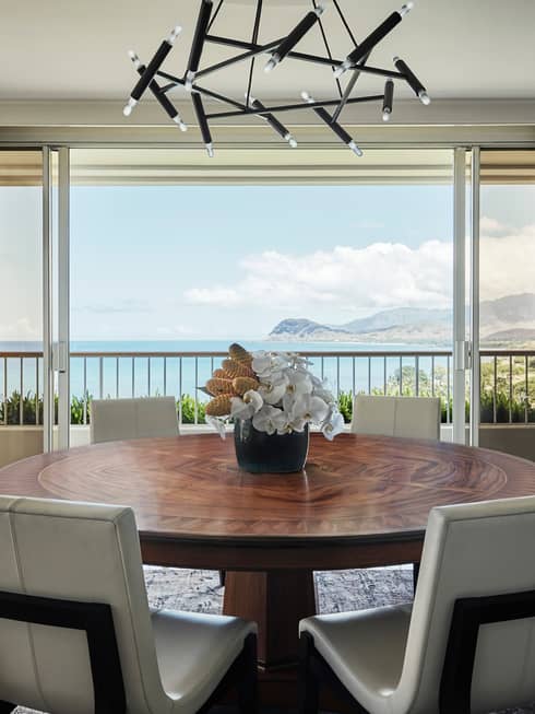 White chairs at large wood dining table under modern black light