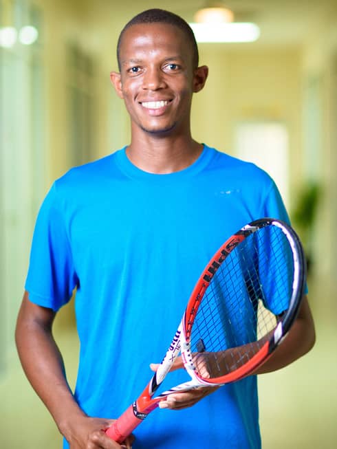 Smiling man in blue shirt holds red tennis racket