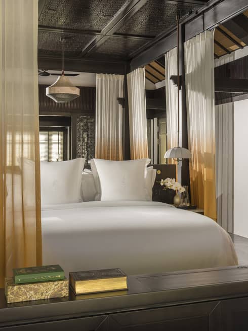 A resort bedroom featuring a king bed with orange and white curtains lining a four-post bed