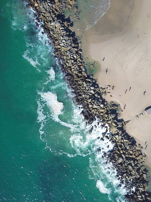 A beach shore with blue waves crashing onto sand.