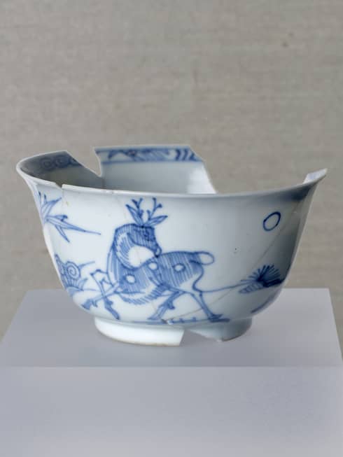 Chipped blue and white Chinese porcelain bowl artefact on display stand