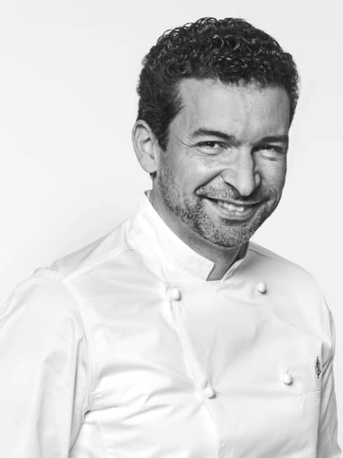Guillaume Cabrol in white chef's coat, hands in pockets, smiling