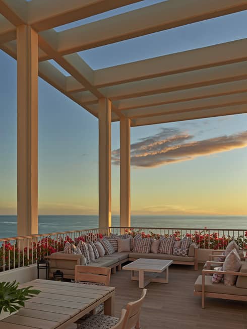 Large lanai overlooking the ocean with lounge furniture and pergola