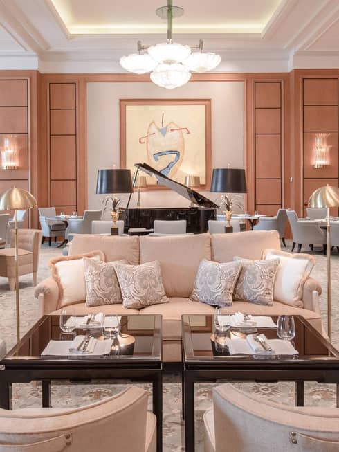 Large lobby with multiple neutral seating areas, black baby grand piano, modern art on wall