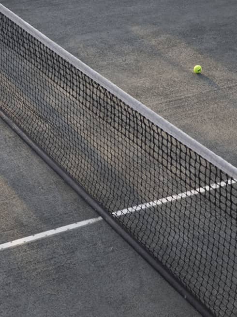 A lone tennis ball lies near the net on an empty court