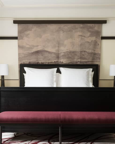 Open black French doors revealing Executive Suite bed, burgundy velvet bench at foot