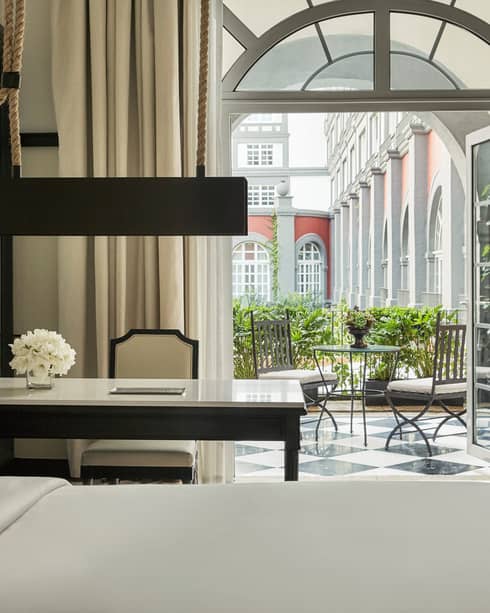 Premier Terrace Room bed, white desk and chair by open French doors to balcony