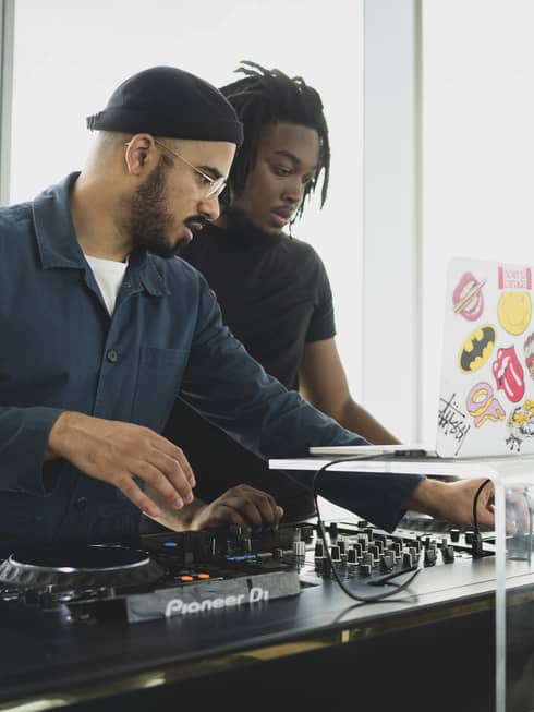 A DJ showing his music setup to a woman to get ready for a show.