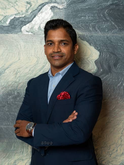 A man in a suit standing in front of a wall.