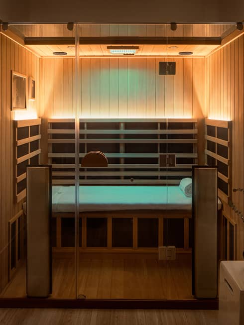 Wooden infrared sauna with lowlighting, side table with vase of eucalyptus