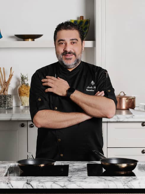 Executive Chef Nicola Rossi in black chef's coat, standing in kitchen with arms crossed