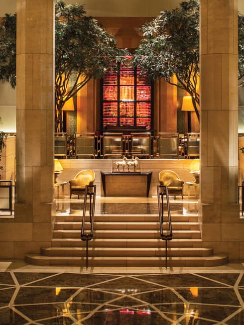 Garden Restaurant marble steps leading up to planters, indoor trees, lounge chairs, horse statues