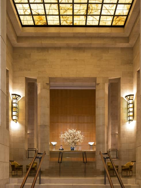 Tall marble columns, steps to hotel reception under amber skylight