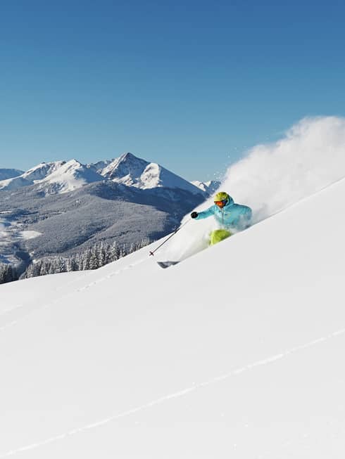 Person skiing down snow covered mountain top