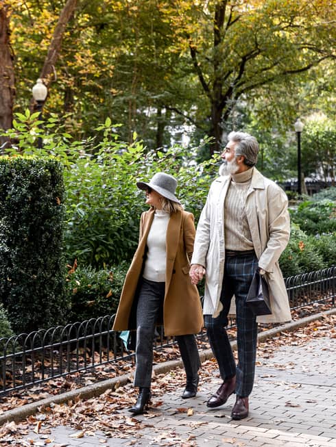 A man and woman walking next to a park.