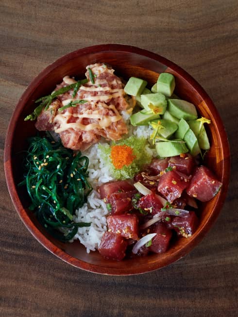 A bowl of poke, the Maui delicacy, stacked with raw fish, avocado, wasabi and greens, all perched on top of a bed of white rice