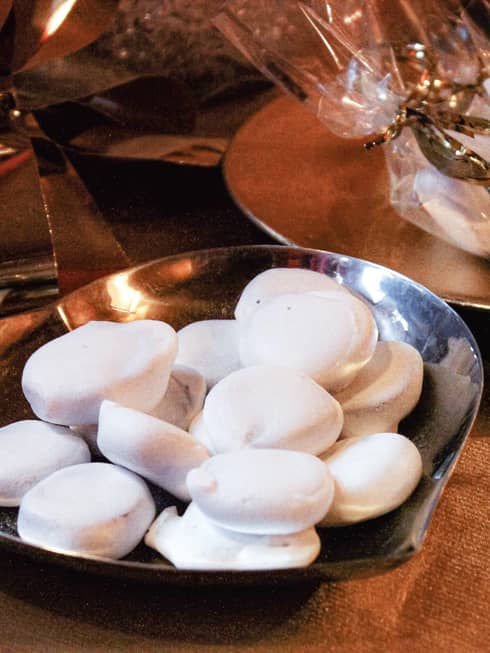 Silver dish filled with white-glazed round mini cookies on wood tabletop
