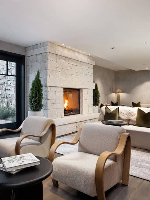 Spa relaxation area with cream sofas and armchairs, in-wall fireplace, glass doors leading to terrace with lounge chairs
