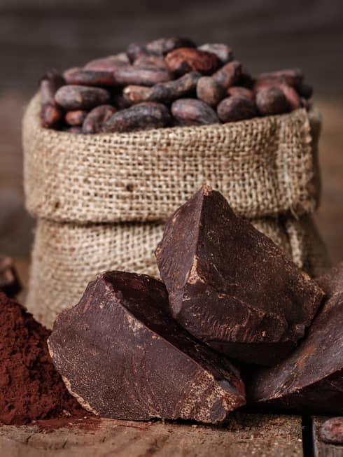 Chunks of chocolate, cocoa powder and coffee beans in a burlap sack