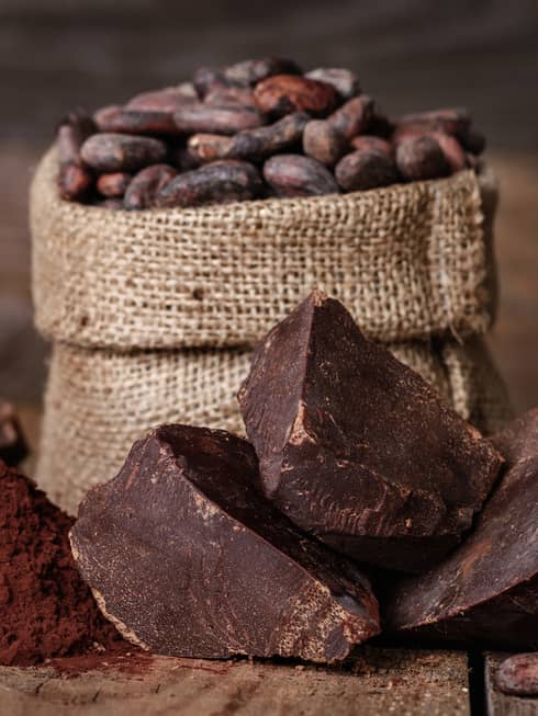 Chunks of chocolate, cocoa powder and coffee beans in a burlap sack