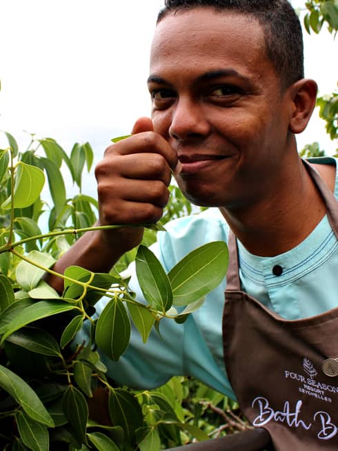 Portrait of bath butler George Monty smiling, smelling lemon tree leaves
