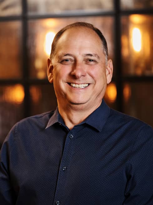 A smiling person wearing a dark shirt