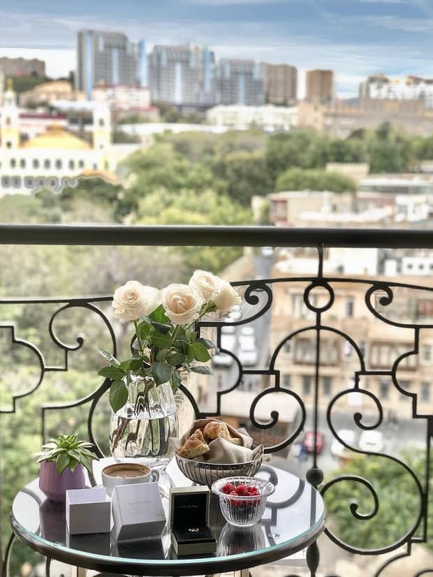 Patio table with wedding rings, flowers, baked goods overlooking sunny city