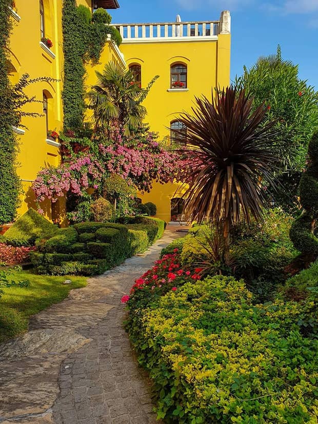 Garden pathway and tropical trees beneath bright yellow building exterior