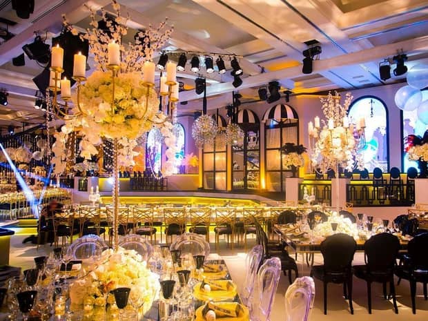 Banquet reception with track lighting over tables with tall candelabras and roses