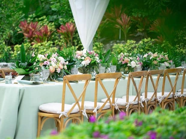 floral arrangement on a long wedding table surrounded by tropical plants