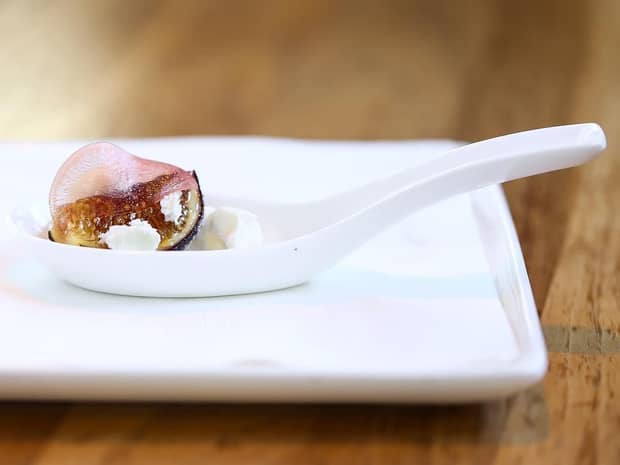 Close-up of small fig dessert on white serving spoon, platter