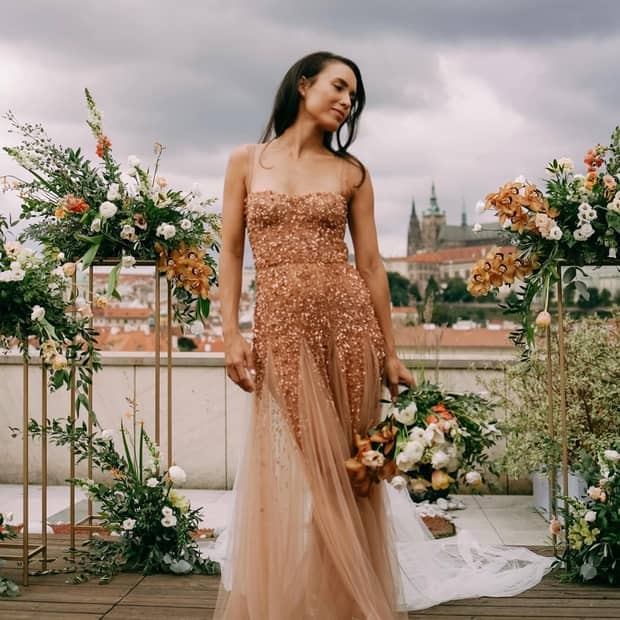 A stunning bride in a golden dress poses on a rooftop, capturing the romantic essence of the wedding.