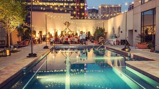 Patio lights strung over outdoor swimming pool by guests on patio cocktail lounge at night