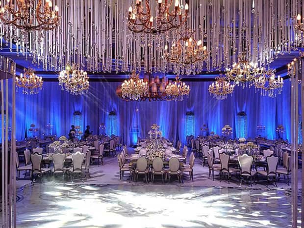 Chandeliers over wedding banquet tables in elegant event room with blue lights