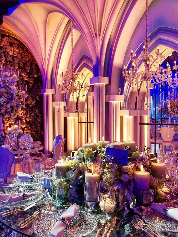 Wedding banquet table with candles, flowers under dramatic archways in event room