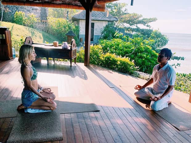 A woman and man sit across from each other while doing yoga