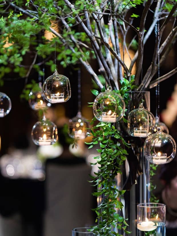 Glass bulbs with tealight candles hang from small tree branches