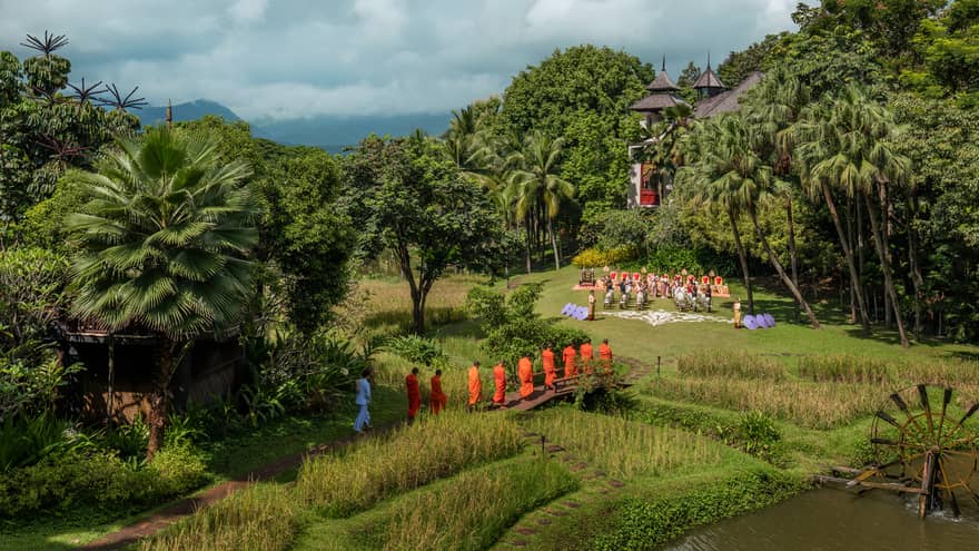 View to tropical lawn, small bridge where people walk toward wedding ceremony