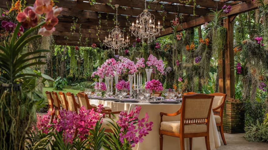 Wedding dining table under chandeliers and wood pergola in tropical garden