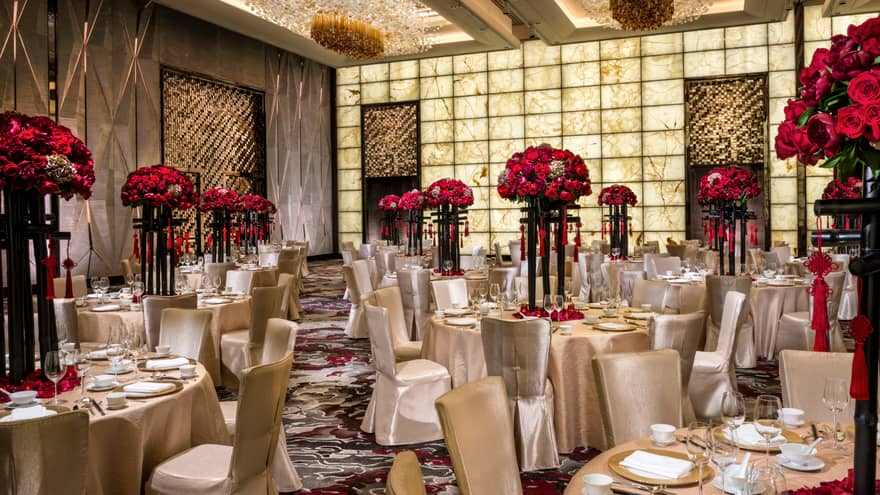Grand Ballroom banquet tables and chairs with silk linens, red flowers in tall vases